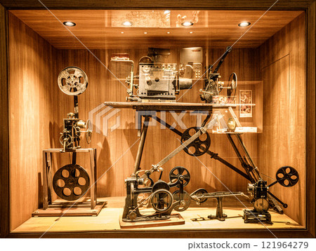 Historic film equipment display showcasing early cinematography techniques in a museum setting. An exhibit featuring vintage film equipment, including projectors and cameras, highlights the evolution Historic film equipment display showcasing early cinematography techniques in a museum setting. An exhibit featuring vintage film equipment, including projectors and cameras, highlights the evolution 121964279