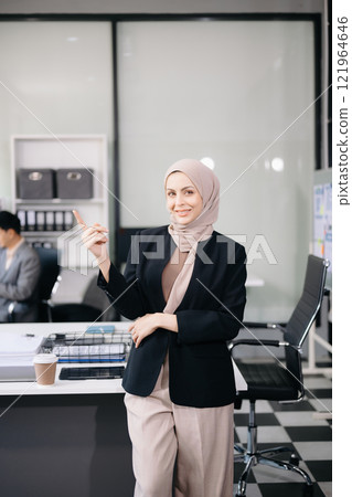 Confident female entrepreneur looking at the camera while standing. Young businesswoman standing in the boardroom Confident female entrepreneur looking at the camera while standing. Young businesswoman standing in the boardroom 121964646