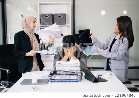 Stressed Asian Businesswoman Surrounded by Overwhelming Paperwork Concept of Workplace Anxiety and Overwork 121964843