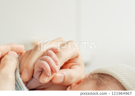 Newborn baby gripping mother's finger 121964967