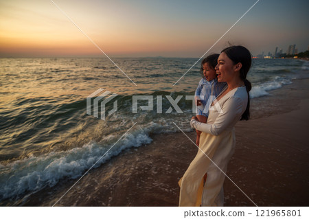 happy mother holding and talking toddler baby girl on sea beach at sunset in Pattaya, Thailand happy mother holding and talking toddler baby girl on sea beach at sunset in Pattaya, Thailand 121965801