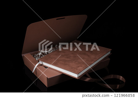 Best gift for men. Man gift concept. Red notebook with red gift box on black background. Copy space. Valentine's day, wedding, birthday and special occasion gift concept. Copy space for text. Best gift for men. Man gift concept. Red notebook with red gift box on black background. Copy space. Valentine's day, wedding, birthday and special occasion gift concept. Copy space for text. 121966858