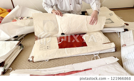 A middle-aged woman unfolds a wrapping paper and looks at an auburn kimono 121966868