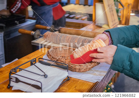 Woman holds in hand Trdlo or Trdelnik, Traditional tasty baked Woman holds in hand Trdlo or Trdelnik, Traditional tasty baked 121966882