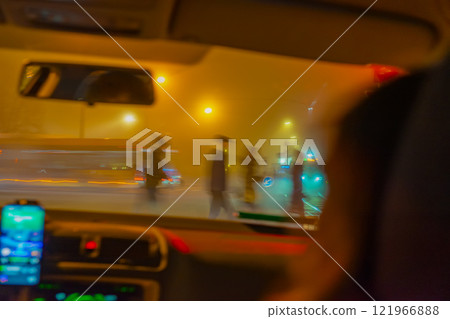 Blurred view of pedestrians crossing a street at night, seen through car windshield. Concept of urban nightlife 121966888