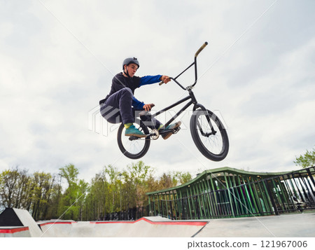 BMX bicycle rider doing stunt Toboggan in quarter pipe. Skilled BMX freestyler athlete jumping over quarter ramp and doing aerial trick Toboggan in street ramp park outdoors BMX bicycle rider doing stunt Toboggan in quarter pipe. Skilled BMX freestyler athlete jumping over quarter ramp and doing aerial trick Toboggan in street ramp park outdoors 121967006