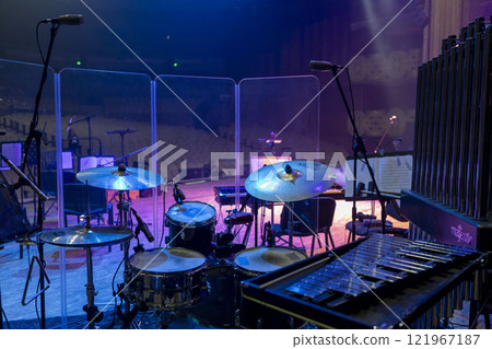 Drum kit, bells and metallophone with microphone support behind a transparent noise-absorbing barrier Drum kit, bells and metallophone with microphone support behind a transparent noise-absorbing barrier 121967187