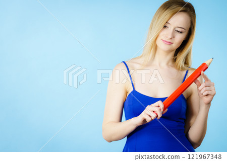Woman confused thinking, big pencil in hand Woman confused thinking, big pencil in hand 121967348