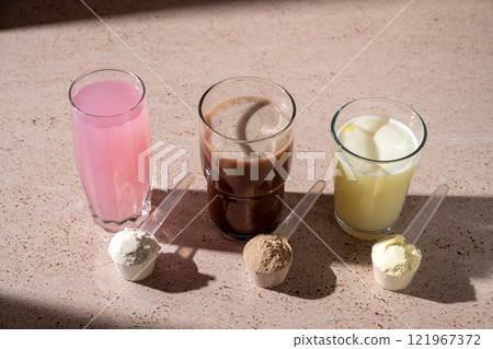 Different protein shake drinks in glasses and protein powder in scoops 121967372
