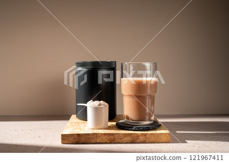 Protein shake and chocolate protein powder in a scoop, food supplement Protein shake and chocolate protein powder in a scoop, food supplement 121967411