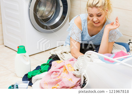 Unhappy girl sorting dirty clothes laundry. Unhappy girl sorting dirty clothes laundry. 121967818