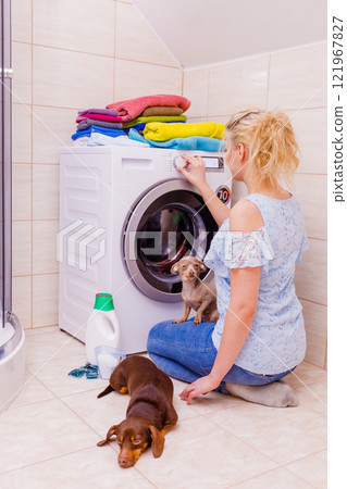 Woman starting washing machine. Woman starting washing machine. 121967827