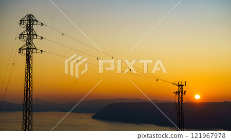 High voltage towers on coast at sunset High voltage towers on coast at sunset 121967978