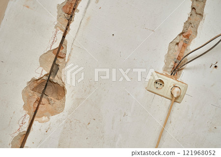 Old brick wall before renovation. Connected socket, wiring, cracks Old brick wall before renovation. Connected socket, wiring, cracks 121968052
