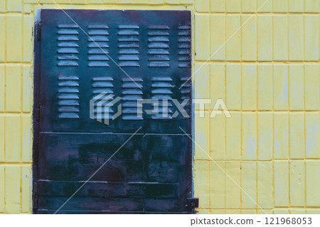 Dark metal grille ventilation holes lattice, wall covered with tiles 121968053