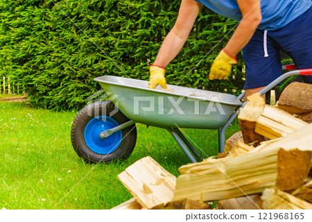 Man loading firewood on wheelbarrow 121968165