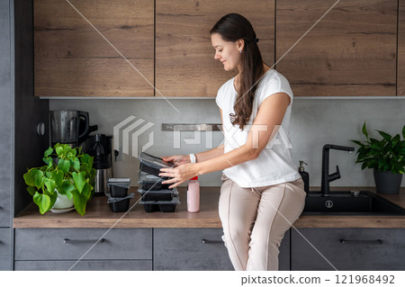 Young woman with healthy diet plan for weight loss, delivery of daily ready meal menu. Food ordered with mobile phone app. Balanced portion with dish. Pre-cooking. Young woman with healthy diet plan for weight loss, delivery of daily ready meal menu. Food ordered with mobile phone app. Balanced portion with dish. Pre-cooking. 121968492