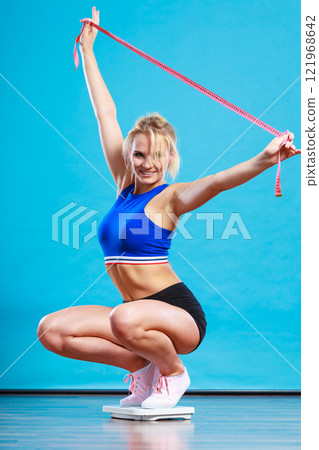 Joyful girl standing on bathroom scales 121968642