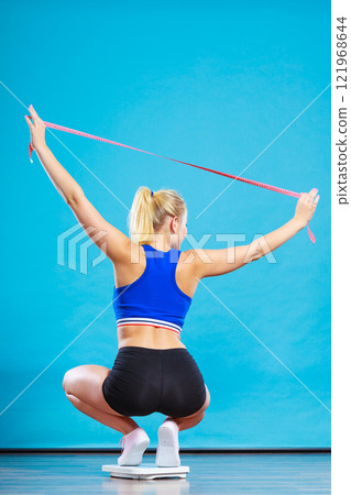 Joyful girl standing on bathroom scales 121968644
