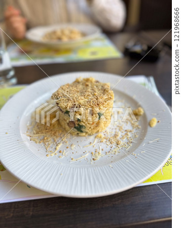Plate of gourmet risotto served with grated cheese and a crispy topping, presented elegantly on a white dish. Culinary sophistication and restaurant concept 121968666