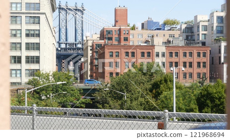New York City Manhattan Bridge view from Brooklyn Bridge. Red brick building, car traffic on road New York City Manhattan Bridge view from Brooklyn Bridge. Red brick building, car traffic on road 121968694