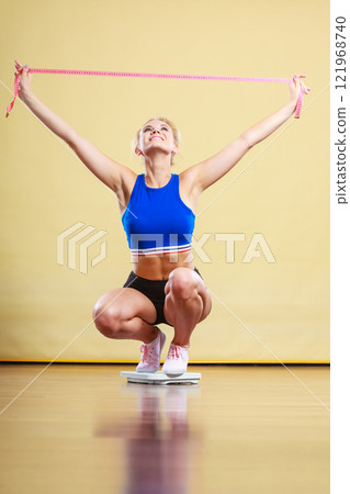 Joyful girl standing on bathroom scales 121968740