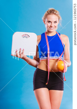 Fit woman holds weight scale grapefruit 121968753