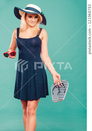 Woman wearing short dress holding flip flops and sunglasses Woman wearing short dress holding flip flops and sunglasses 121968783