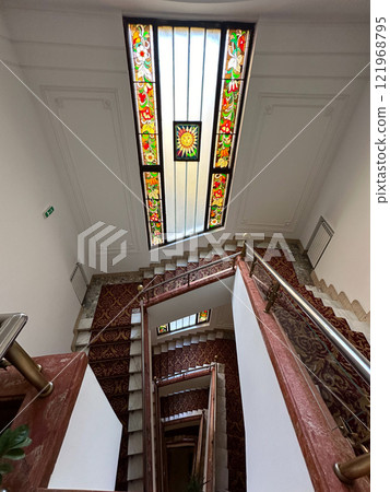 Spiral staircase with a vibrant stained-glass ceiling showcasing intricate patterns and colorful motifs. the artistic design and elegant decor a sense of timeless beauty and architectural mastery in 121968795