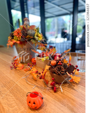 Festive autumn table arrangement with vibrant fall decorations and a miniature pumpkin. Warm tones and cozy ambiance evoke the spirit of the harvest season and Halloween celebrations 121968837