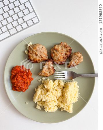 Homemade meal served on a neutral plate, featuring couscous, meat patties and a side of ajvar. Simplicity and balance of the dish reflect a casual yet thoughtful approach to everyday dining. Lunch Homemade meal served on a neutral plate, featuring couscous, meat patties and a side of ajvar. Simplicity and balance of the dish reflect a casual yet thoughtful approach to everyday dining. Lunch 121968850