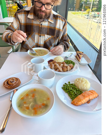 Hearty lunch served at a bright, modern cafe with a variety of dishes. Warm inviting atmosphere and delicious food create a perfect setting for a relaxed dining experience 121968866
