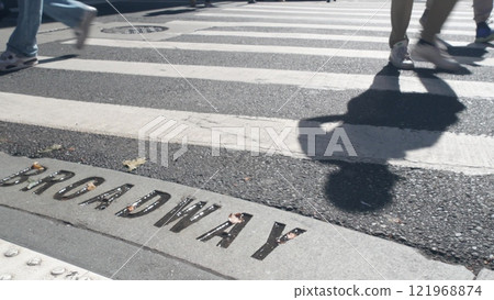 Broadway street sign, people on pedestrian zebra crossroad. New York City Manhattan road intersection 121968874