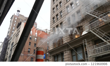 Steam vapor vented, New York City street steam system, orange vapour tube stack. Hot smoke from pipe Steam vapor vented, New York City street steam system, orange vapour tube stack. Hot smoke from pipe 121968906