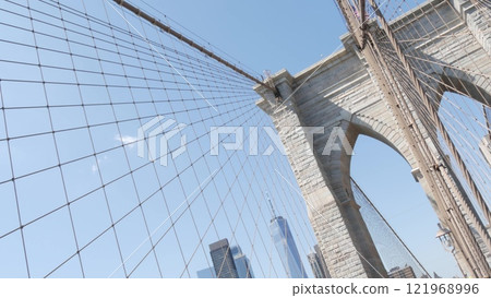 Brooklyn Bridge to Manhattan downtown, cables and blue sky. New York City iconic symbol. Travel USA. Brooklyn Bridge to Manhattan downtown, cables and blue sky. New York City iconic symbol. Travel USA. 121968996