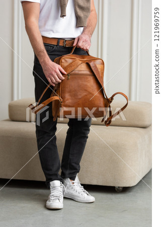 A Stylish and Man standing with a yellow brown backpack in a Contemporary Modern Setting 121969759