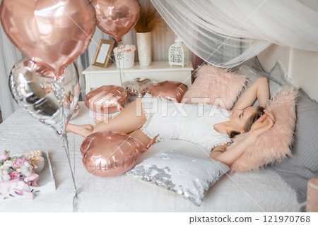 Beautiful young girl at home on the bed in the morning enjoy valentines day celebration with heart shaped balloons 121970768