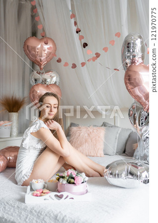 Beautiful young girl at home on the bed in the morning enjoy valentines day celebration with heart shaped balloons 121970775