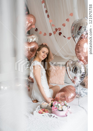 Beautiful young girl at home on the bed in the morning enjoy breakfast and valentines day celebration with heart shaped balloons Beautiful young girl at home on the bed in the morning enjoy breakfast and valentines day celebration with heart shaped balloons 121970788