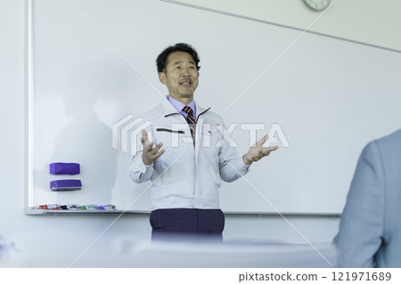 A middle-aged man in work clothes talking in front of a whiteboard. Photo courtesy of Tokyo Electronics College, Denpa Gakuen Corporation. A middle-aged man in work clothes talking in front of a whiteboard. Photo courtesy of Tokyo Electronics College, Denpa Gakuen Corporation. 121971689