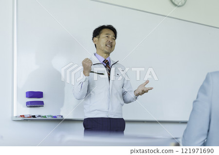 A middle-aged man in work clothes talking in front of a whiteboard. Photo courtesy of Tokyo Electronics College, Denpa Gakuen Corporation. A middle-aged man in work clothes talking in front of a whiteboard. Photo courtesy of Tokyo Electronics College, Denpa Gakuen Corporation. 121971690