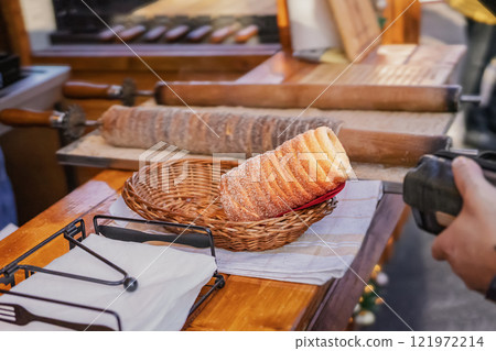 Trdelnik is baked delicacy on a spit, spiral dough with sugar, cinnamon and vanilla, street food 121972214