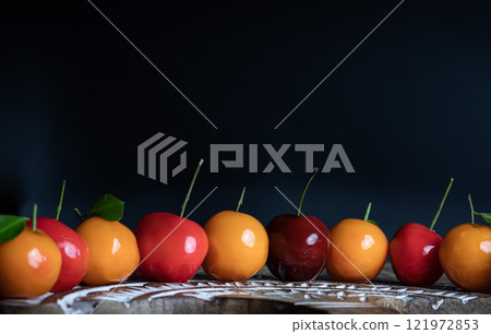 View of Deletable imitation fruits (Kanom look choup) in the shape of fruits has a sweet taste on wooden cutting board. 121972853