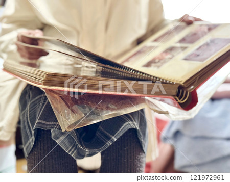 老婦人從前面翻閱一本厚厚的相冊 老婦人從前面翻閱一本厚厚的相冊 121972961