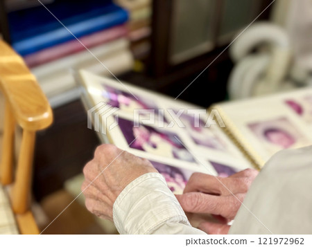 Elderly woman turning the pages of an album Elderly woman turning the pages of an album 121972962