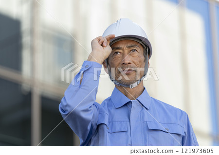 一名60多歲的男子戴著頭盔,穿著工作服 一名60多歲的男子戴著頭盔,穿著工作服 121973605
