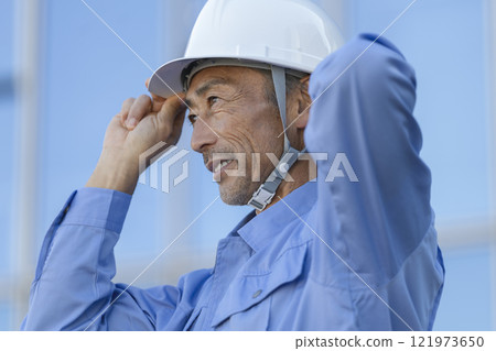 Profile of a veteran worker in work clothes and a helmet 121973650