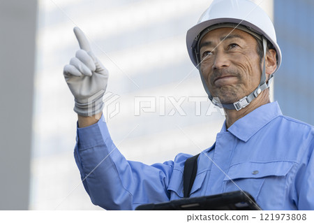 一名穿著工作服的男子正在檢查建築物 一名穿著工作服的男子正在檢查建築物 121973808