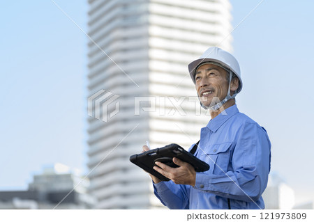 A man in work clothes carrying out inspection work with a tablet 121973809