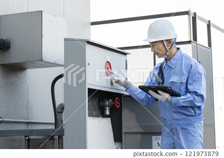 Man in work clothes inspecting outdoor fire hydrant equipment Building maintenance image 121973879